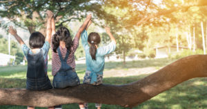 Children friendship concept with happy girl kids in the park having fun sitting under tree shade playing together enjoying good memory and moment of student lifestyle with friends in school time day