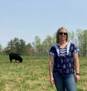 April Bowman in a pasture with a black cow.