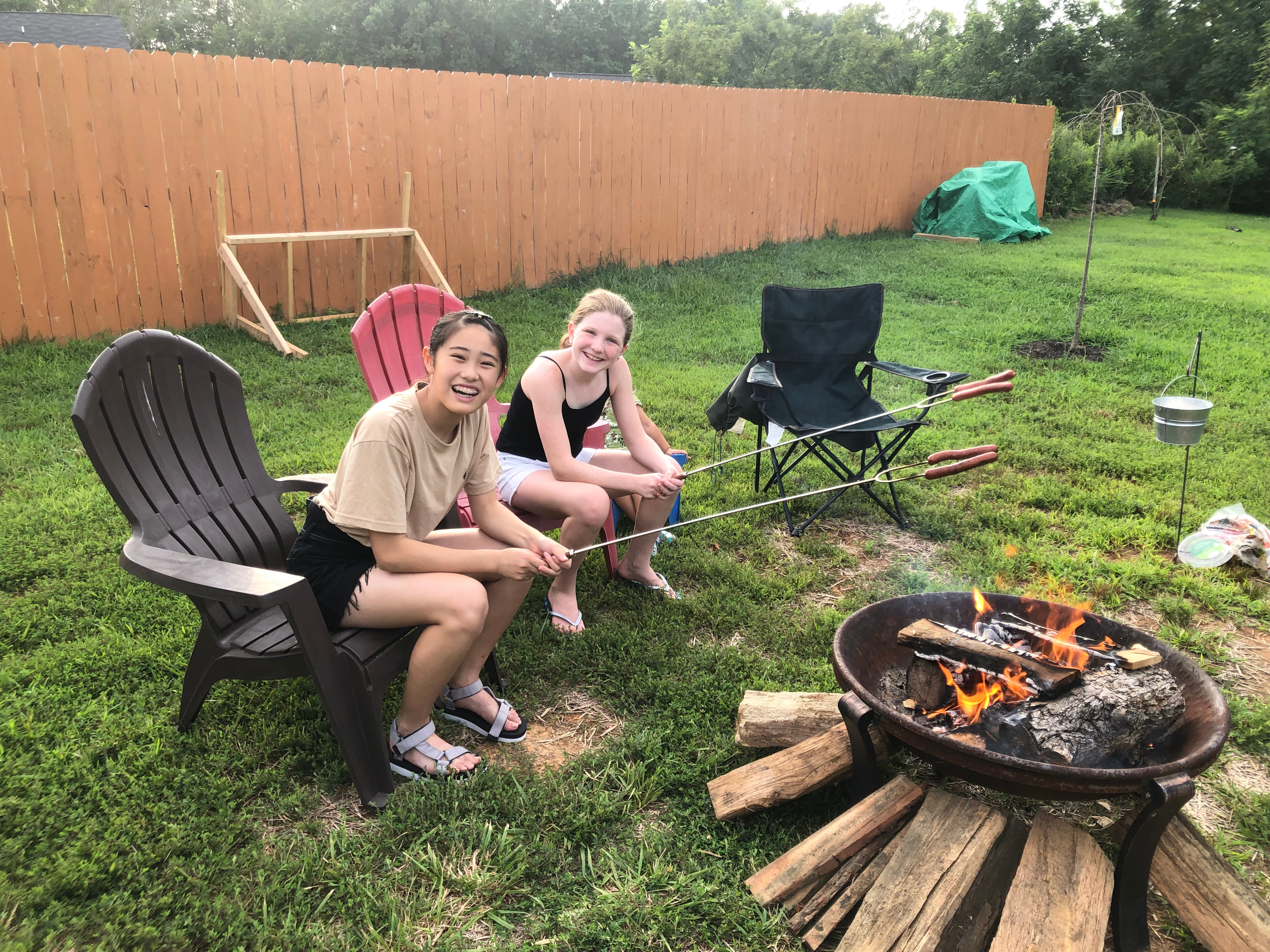 A Japanese Exchange student and her American host sit by a campfire